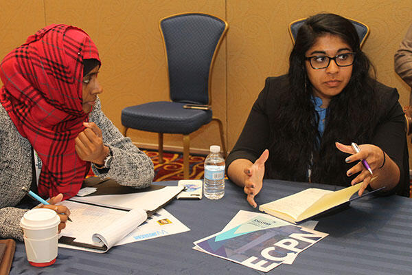 two Middle Eastern women at a table discussing coursework